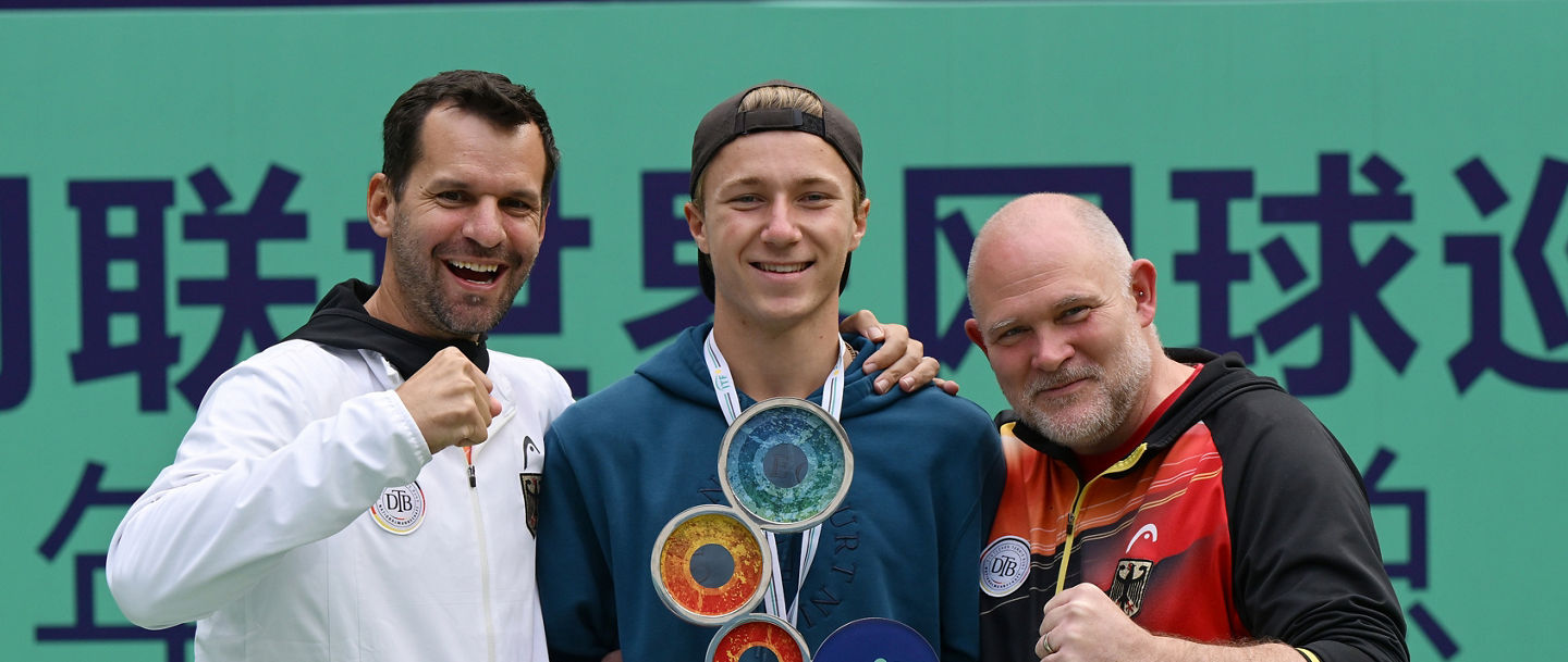 Max Schönhaus mit Pokal und den beiden DTB-Bundestrainern Philipp Petzschner und Björn Simon.