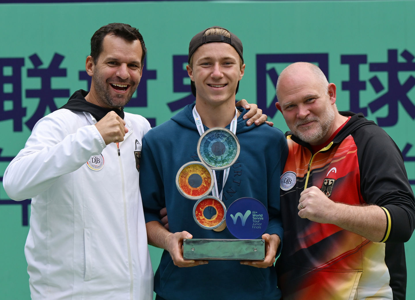 Max Schönhaus mit Pokal und den beiden DTB-Bundestrainern Philipp Petzschner und Björn Simon.