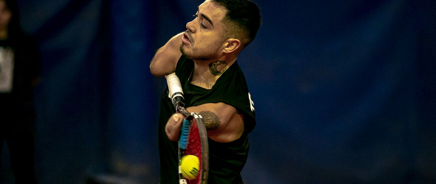 Tennis player mid-swing on indoor court