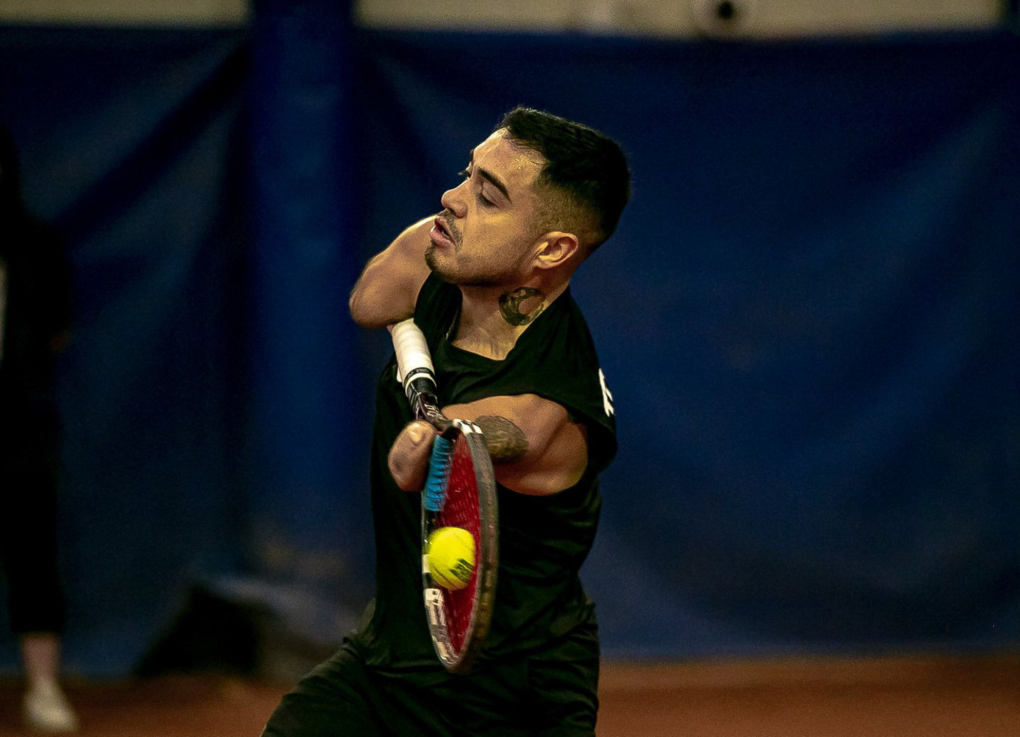 Tennis player mid-swing on indoor court