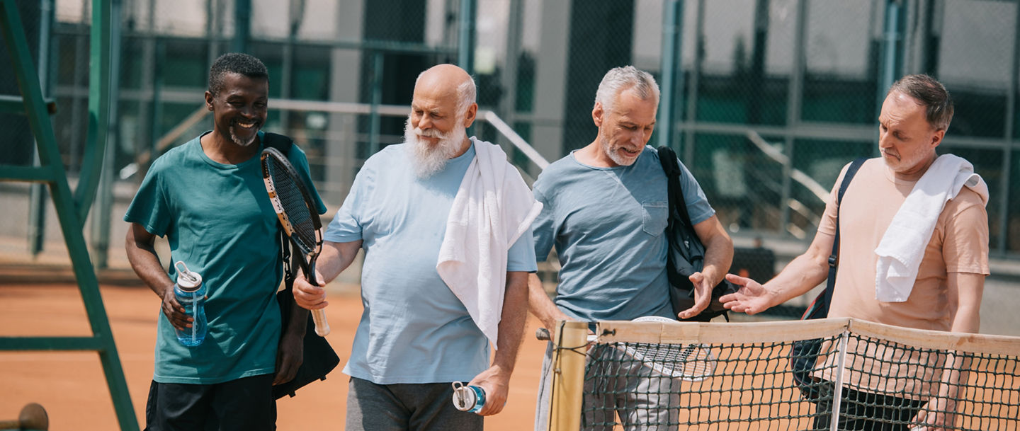 portrait of smiling multiracial elderly friends with tennis equipment on court