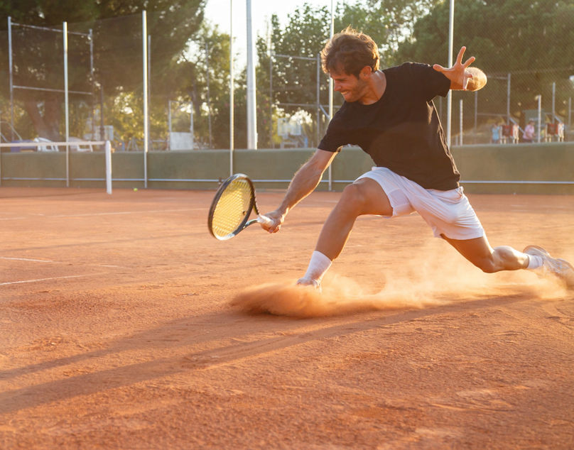 Tennisspieler rutscht auf Sandplatz