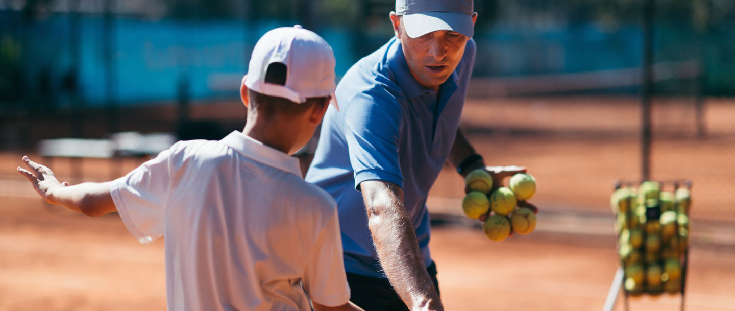 Tennis instructor with young boy in tennis training lesson