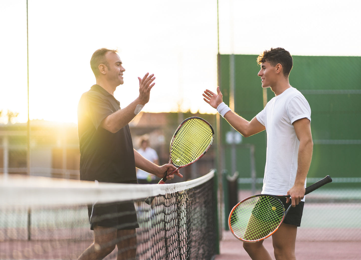 Father and Son Playing Tennis Outdoors.