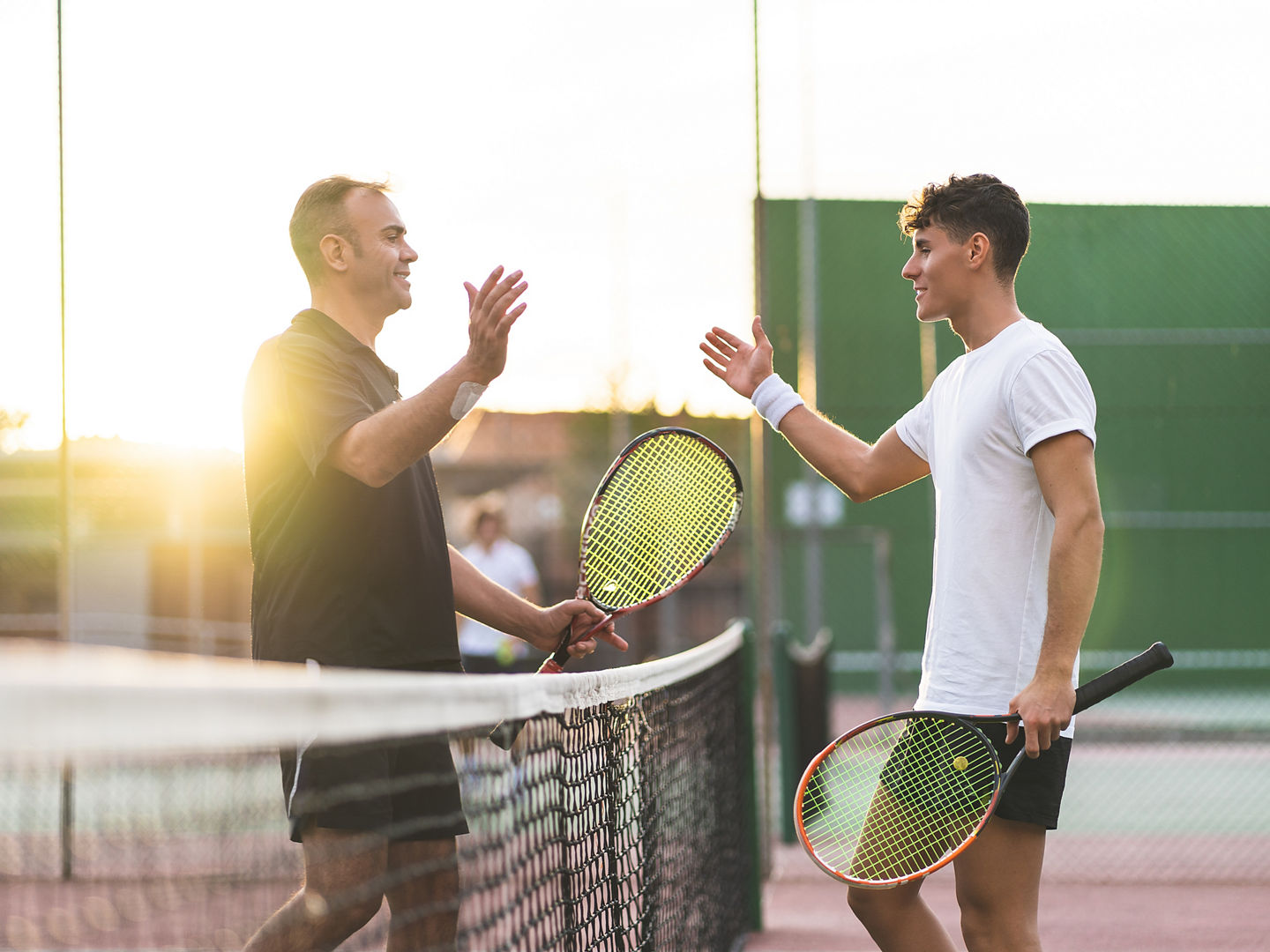 Father and Son Playing Tennis One to One. Family Doing Sport Together . Father Giving a Hug to His Son After Playing Tennis. Family Concept.