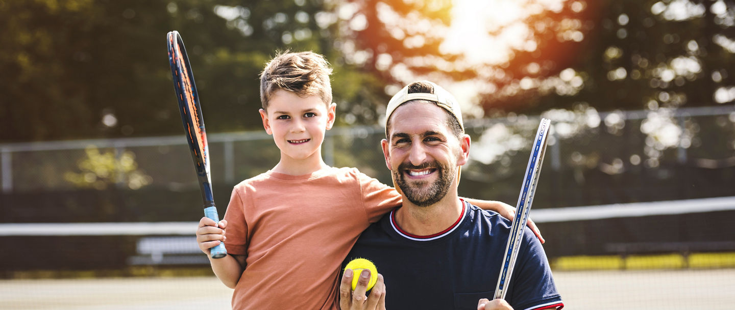 A Father and son play tennis on a summer day