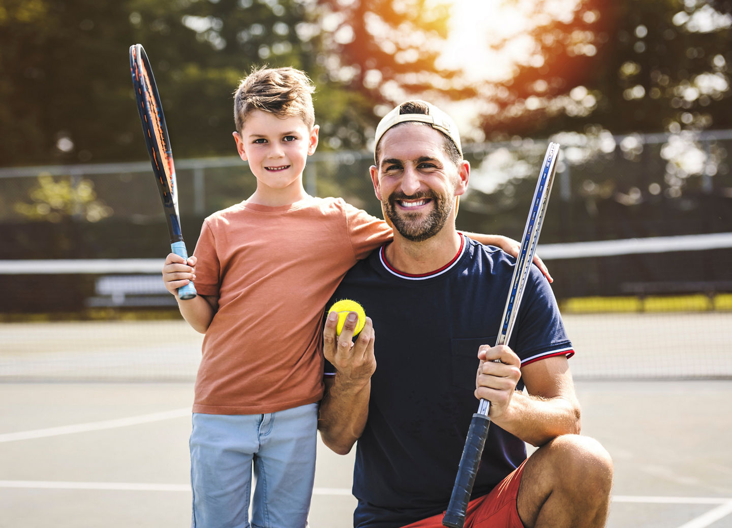 A Father and son play tennis on a summer day