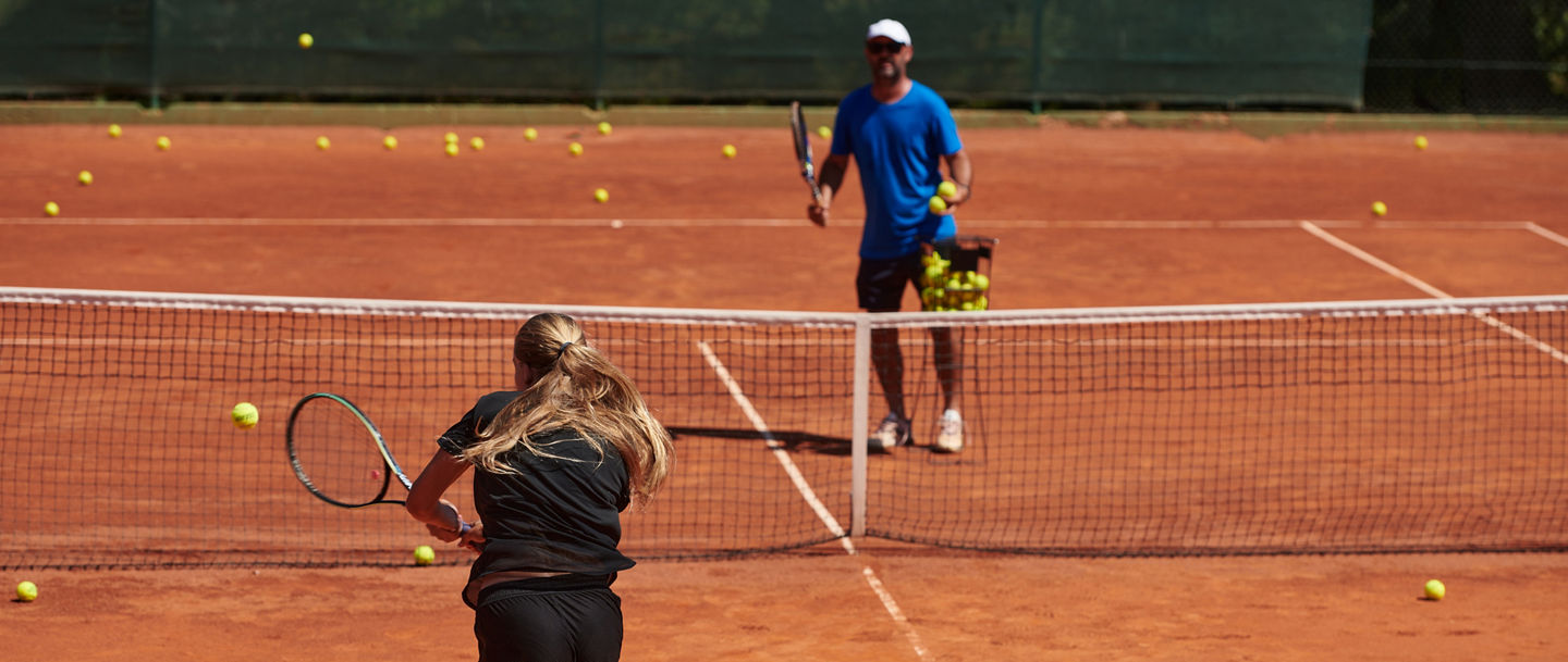 A professional tennis player and her coach training on a sunny day at the tennis court. Training and preparation of a professional tennis player.
