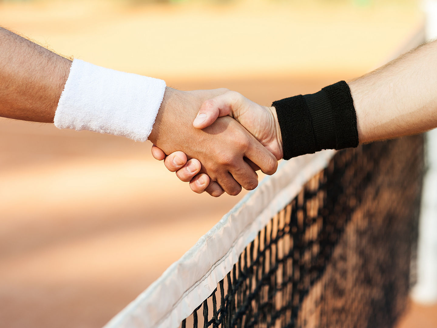 Handshake over tennis net on clay court