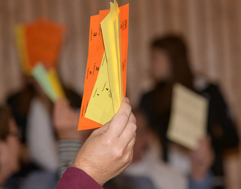 Hand streckt Stimmkarten in die Höhe