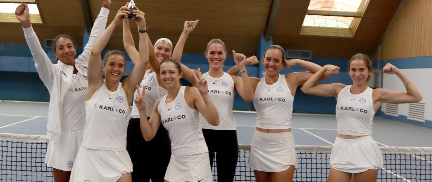Women's tennis team celebrating victory indoors