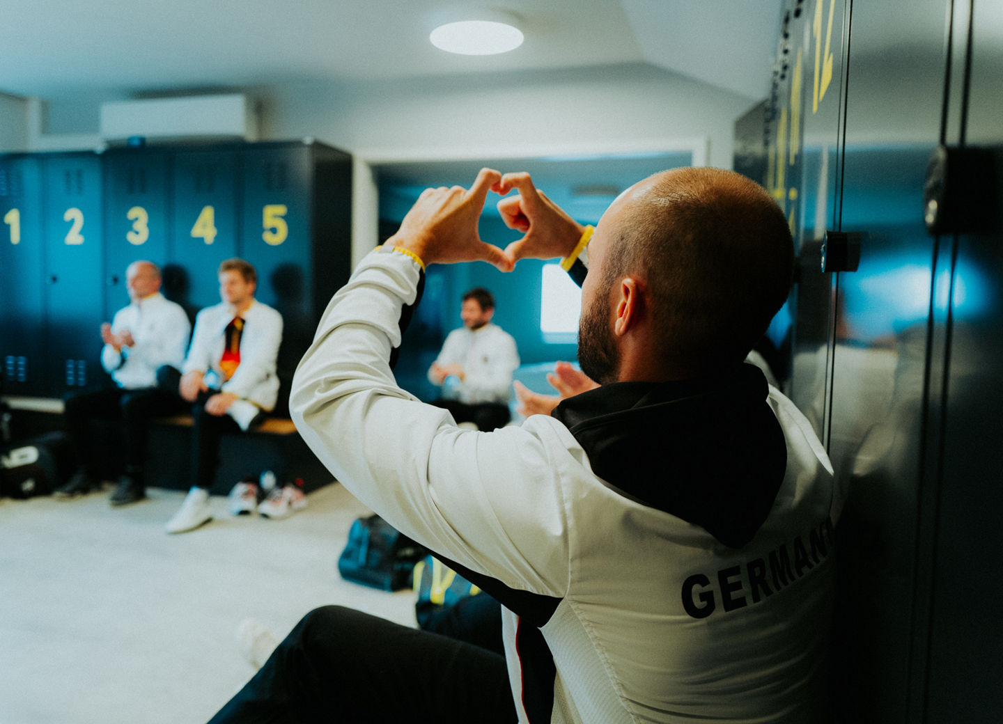 Tim Pütz formt in der Teamkabine beim Davis Cup seine Hände zu einem Herz