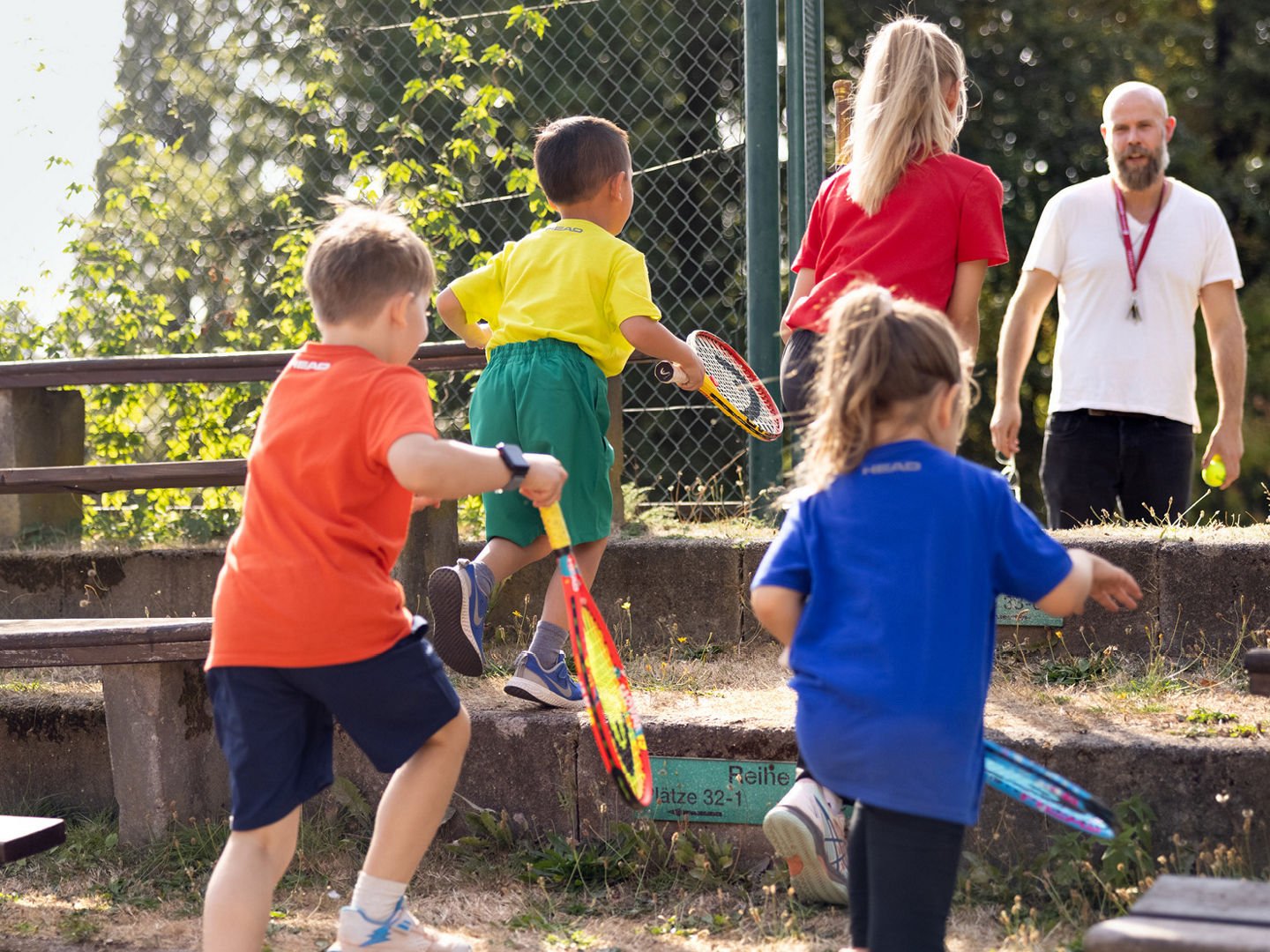 Eine Gruppe von Kindern läuft Stufen mit Tennisschlägern in der Hand hoch