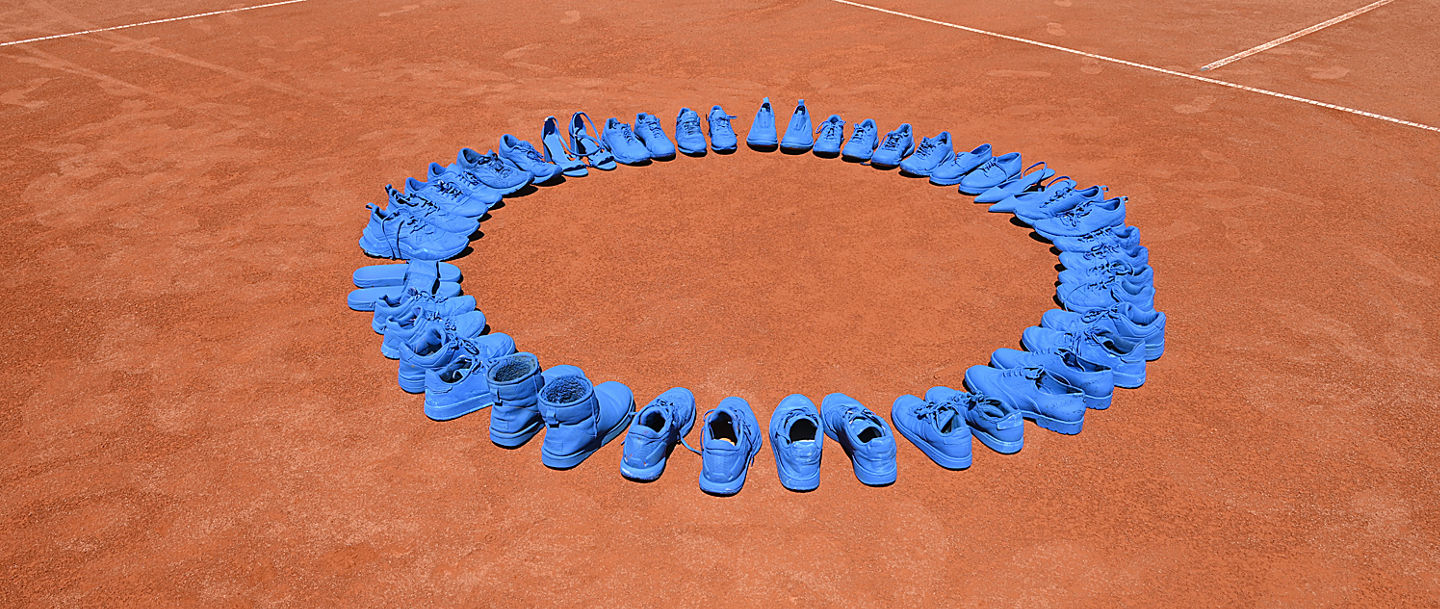Blau angemalte Schuhe stehen auf dem Tennisplatz des BTV 