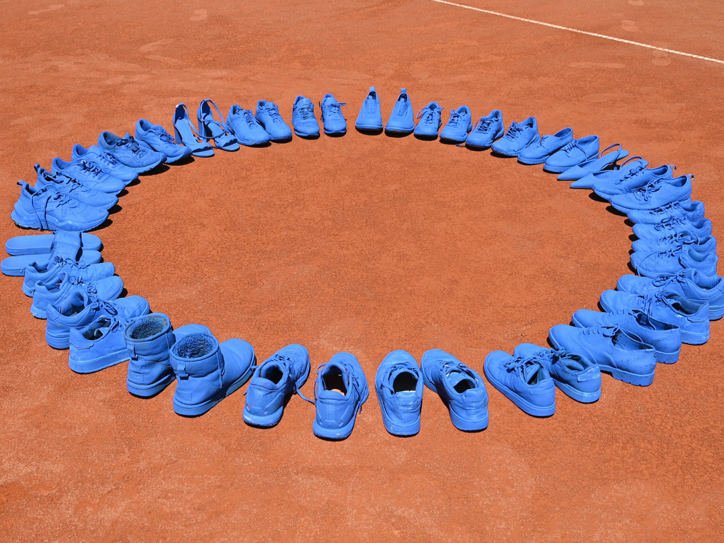 Blau angemalte Schuhe stehen auf dem Tennisplatz des BTV 