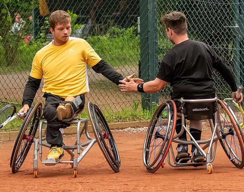 Zwei Rollstuhl-Tennisspieler klatschen sich ab