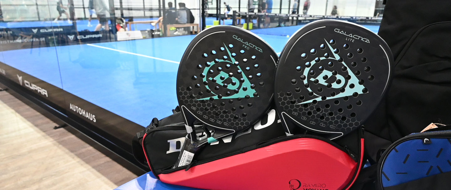 Padelschläger im Vordergrund, ein Padelcourt im Hintergrund