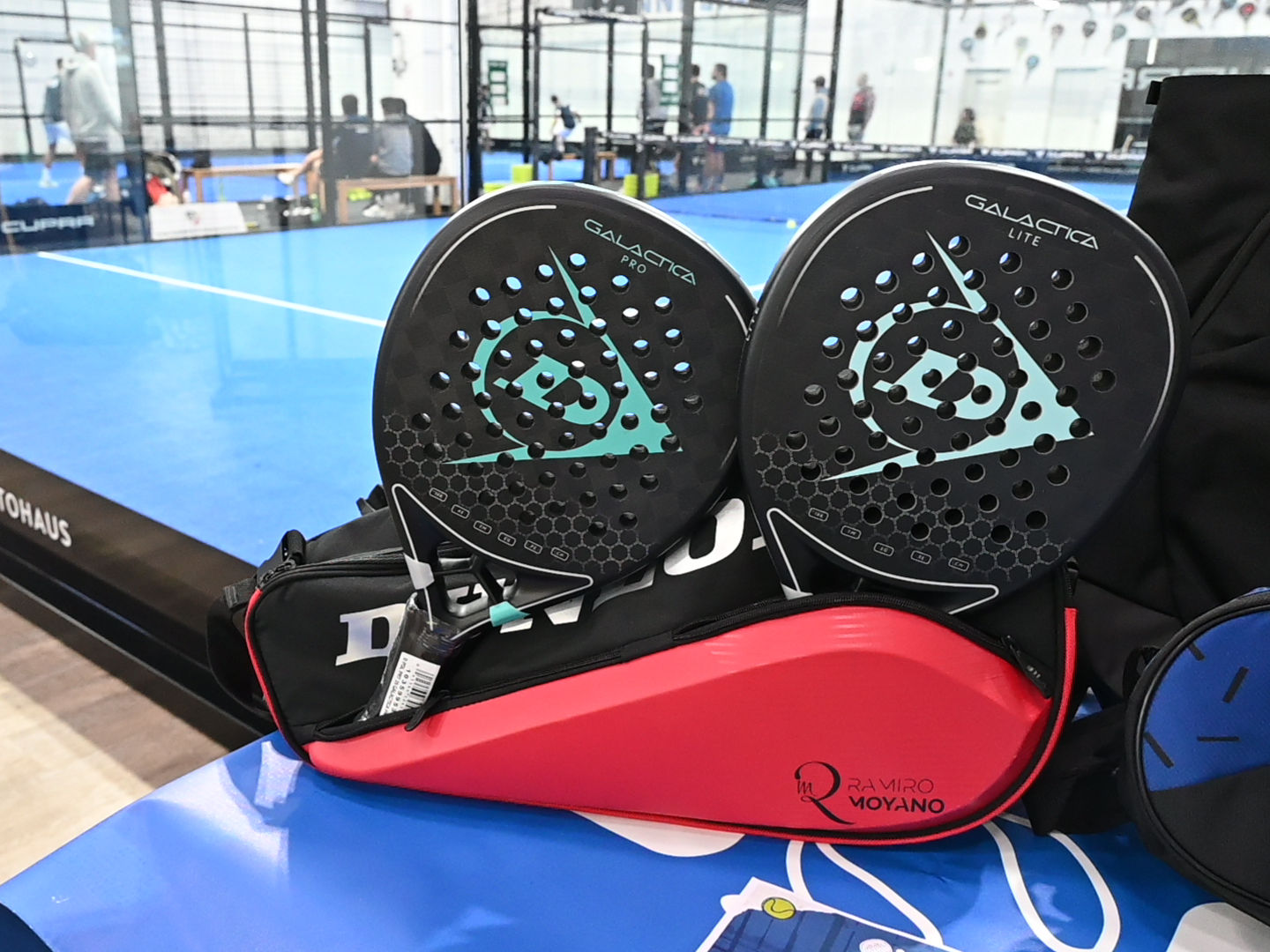 Padelschläger im Vordergrund, ein Padelcourt im Hintergrund