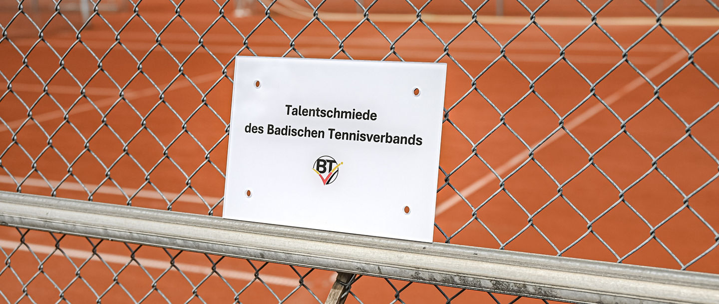 Talentschmieden_Schild_mit_Tennisplatz_im_Hintergrund