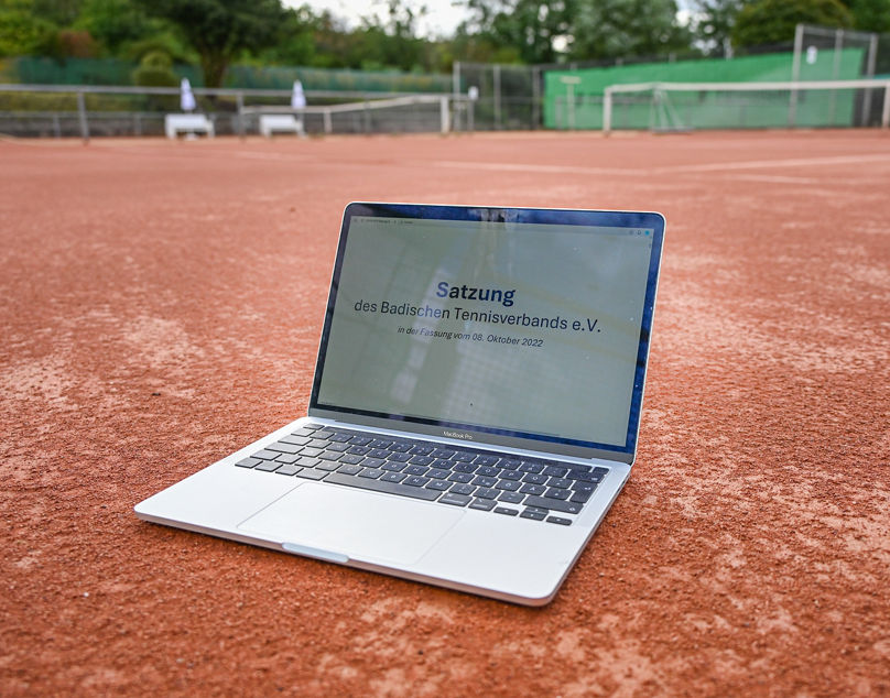 Laptop mit geöffneter Satzung auf Tennisplatz