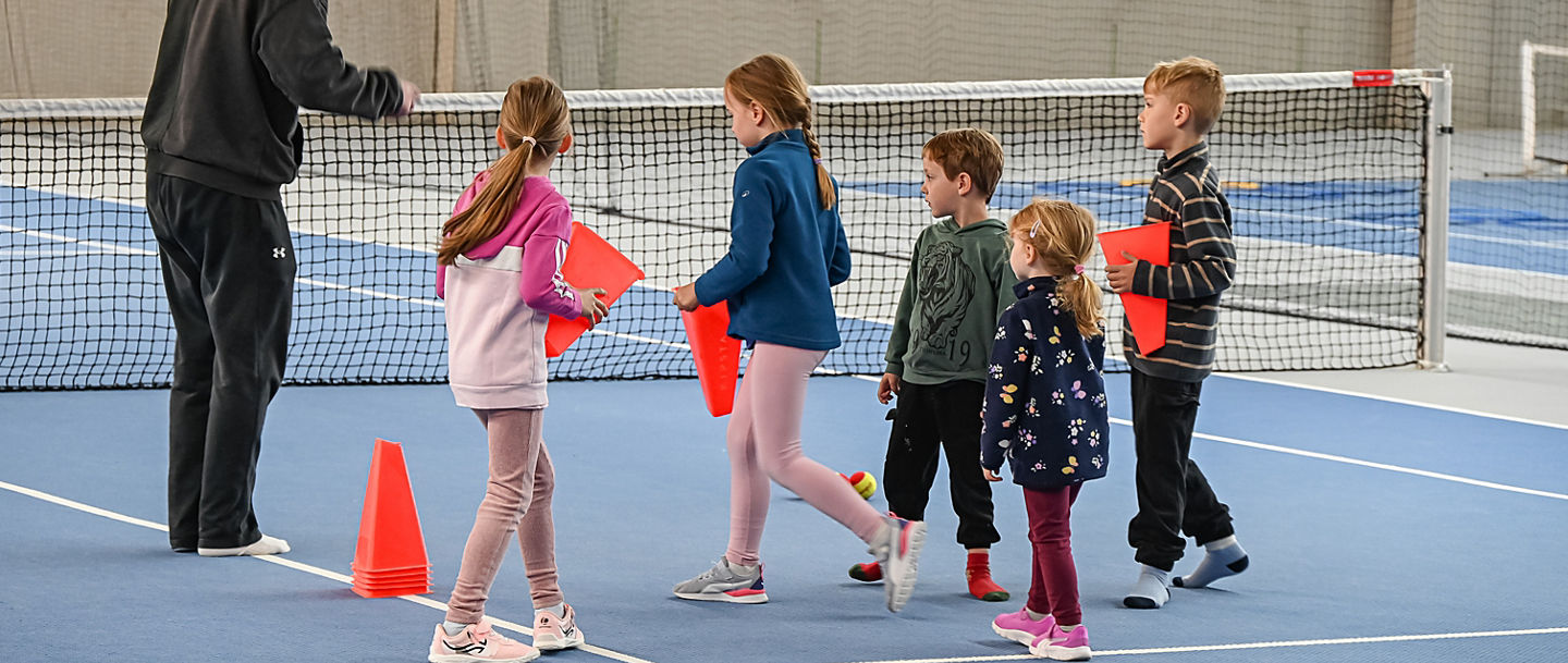 Fünf Kinder beim Aufbau einer Übung mit einem Trainer