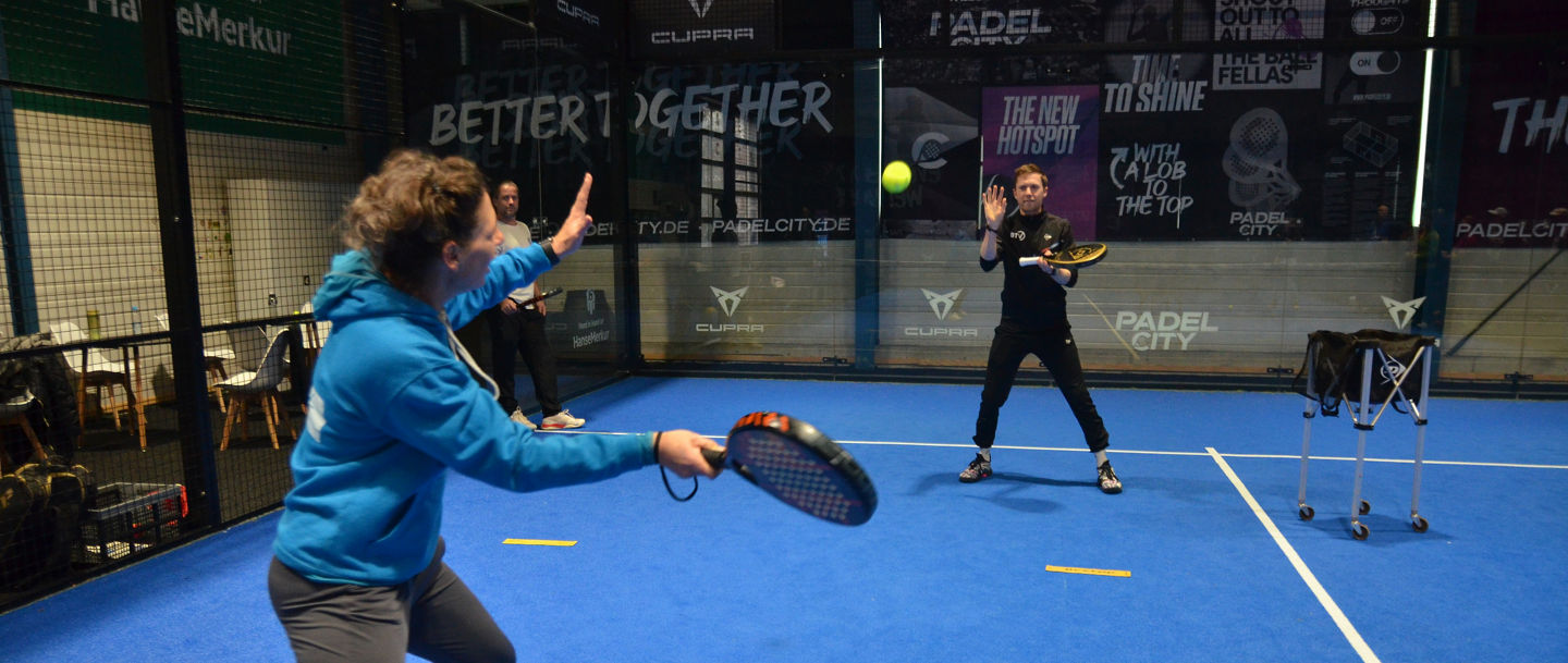 Ausgebildete Padel-Trainer erklären eine Übung.