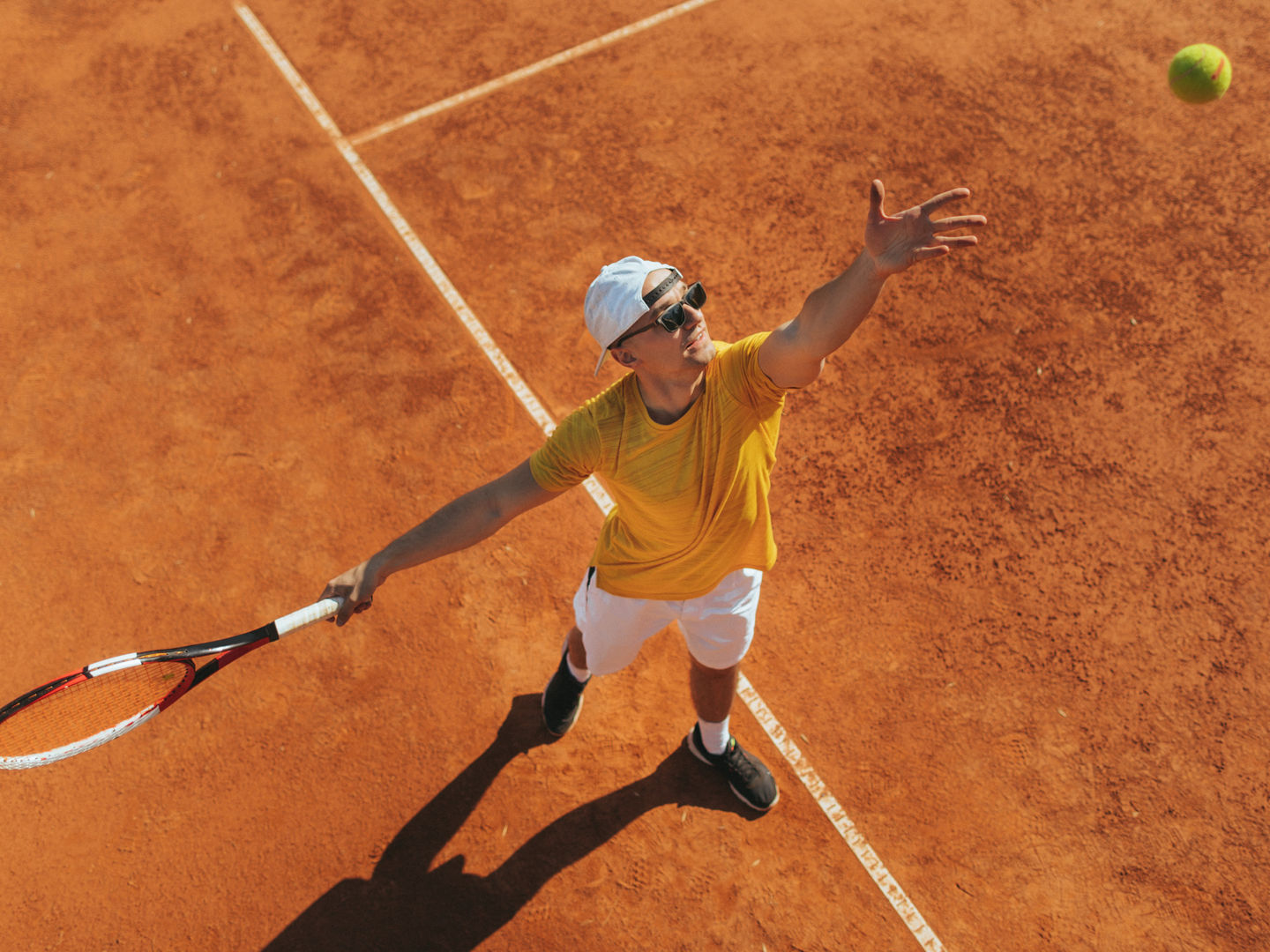 Tennisspieler von oben beim Ballwurf für den Aufschlag