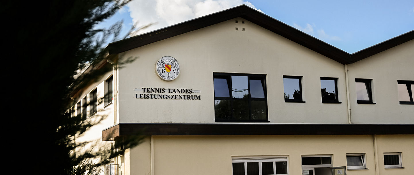 Fronatlansicht des LLZ Leimen mit altem BTV-Logo und Schriftzug "Tennis Landesleistungszentrum" an der Fassade