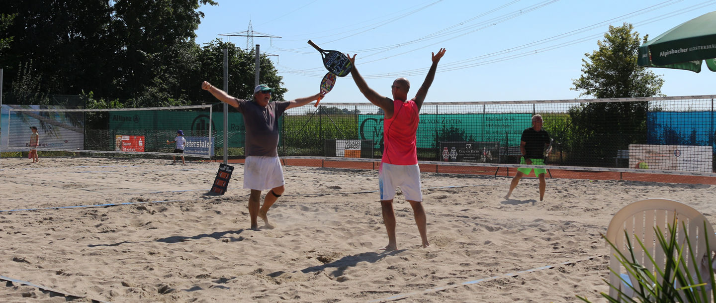 Zwei Beach Tennis Spieler jubeln im Sand