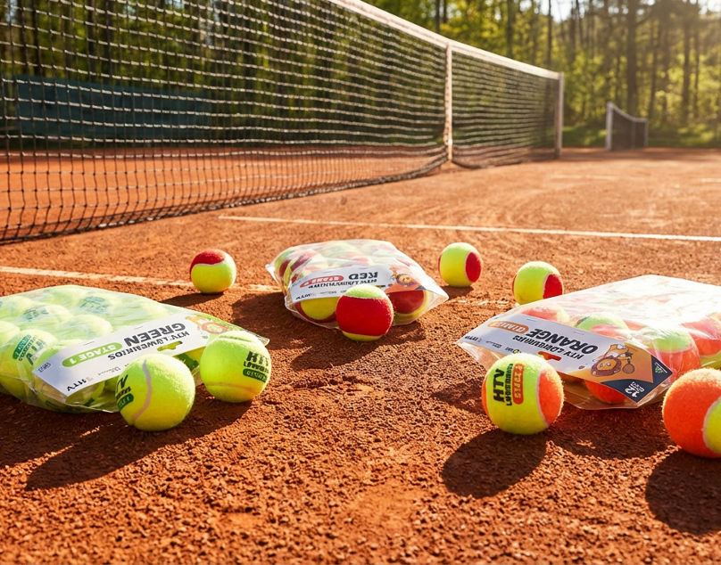 Tennis balls on clay court in sunlight