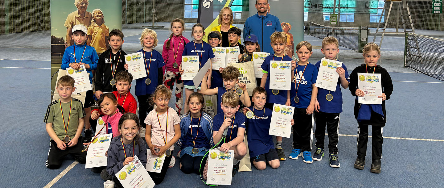 Teilnehmende des STB-Kids-Cup in Merzig in der Tennishalle vor dem Netz zum Gruppenfoto aufgestellt