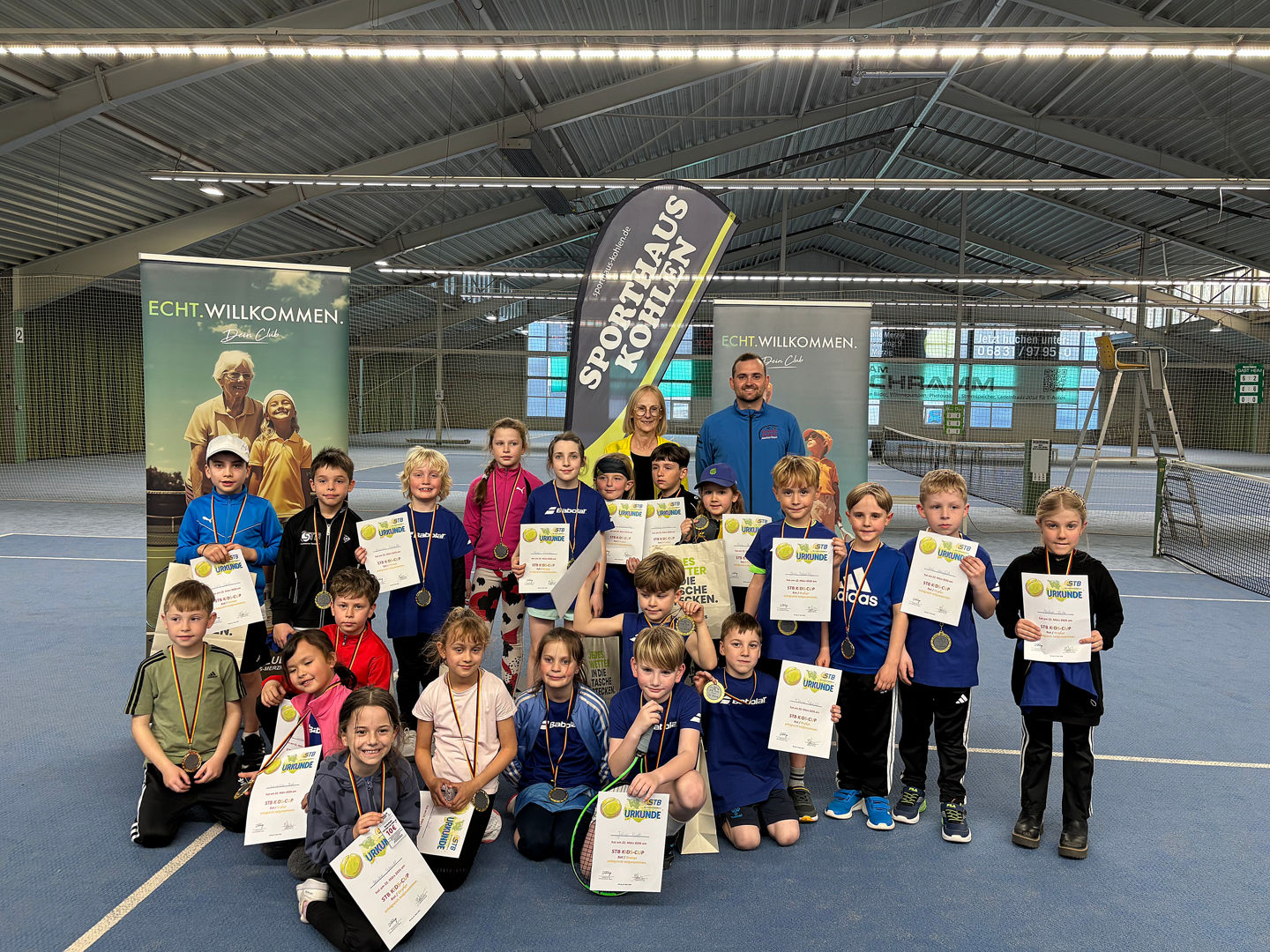 Teilnehmende des STB-Kids-Cup in Merzig in der Tennishalle vor dem Netz zum Gruppenfoto aufgestellt
