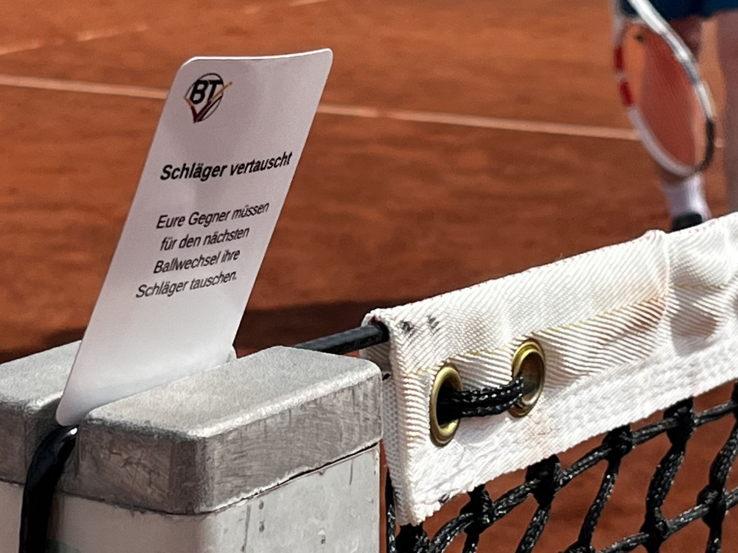 Eine Jokerkarte vor dem Netz auf dem Tennisplatz