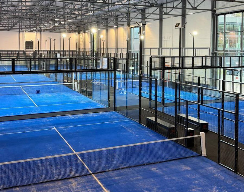 Bild der Padelhalle innen mit 8 nebeneinanderliegenden Plätzen