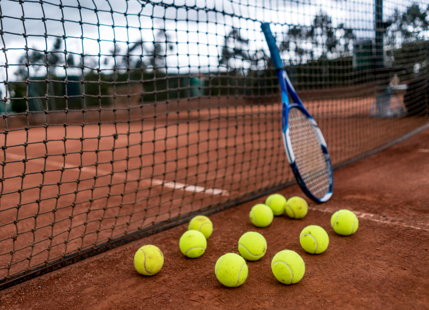 Tennisschläger und Tennisbälle vor einem Tennisnetz