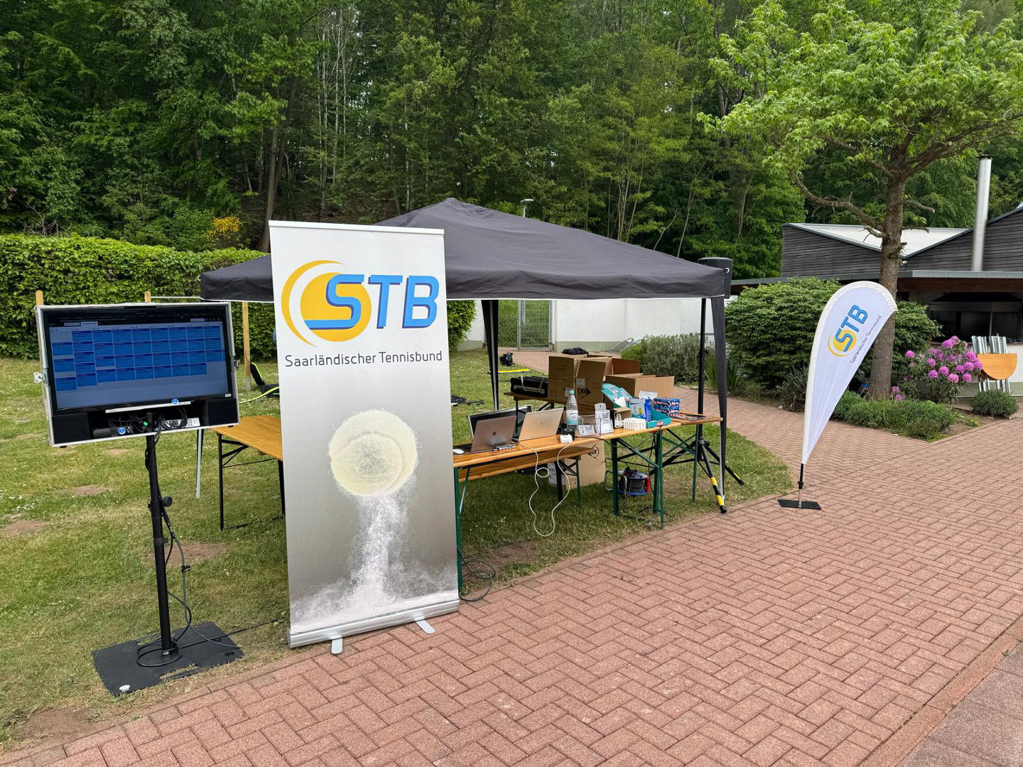Zelt auf der Tennisanlage, unter dem ein Tisch und Equipment der Turnierleitung steht