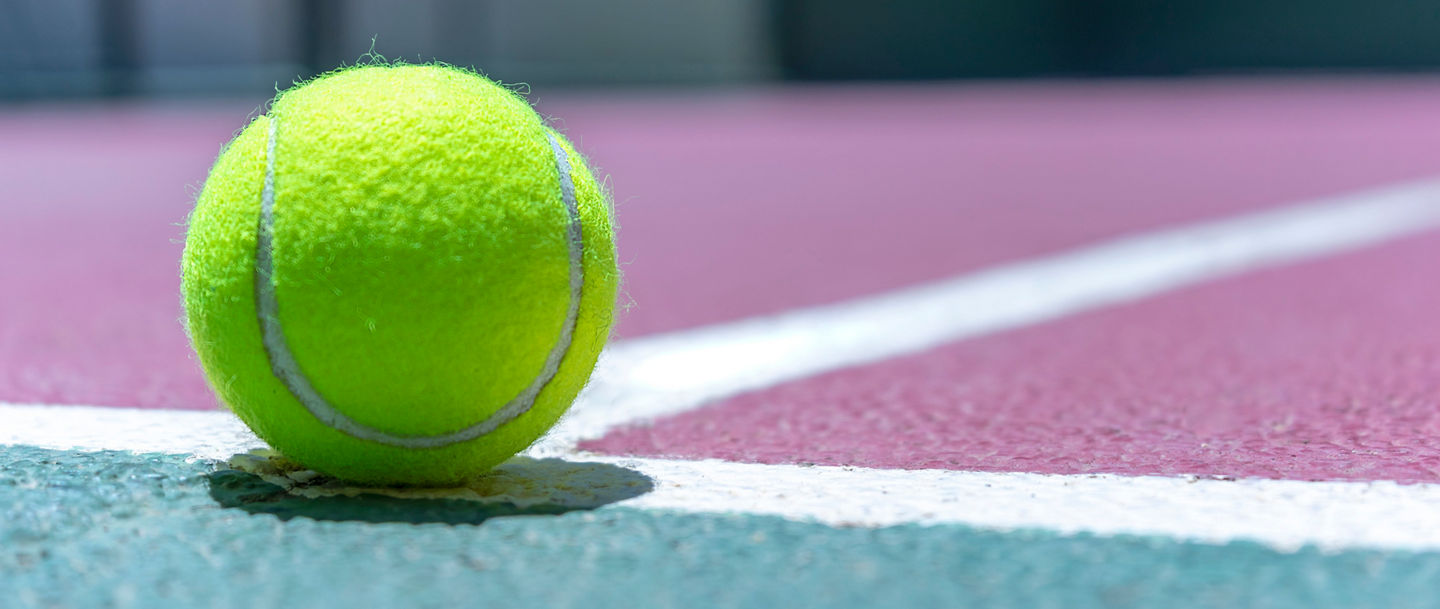 CLOSE UP OF A TENNIS BALL ON THE PADEL COURT.