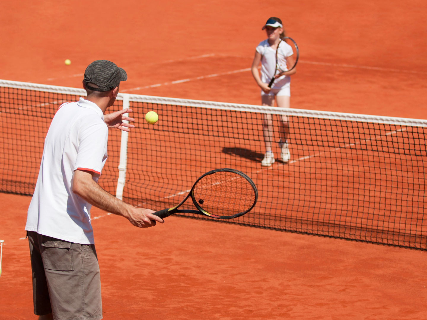 Tennistrainer mit Schülerin auf dem Sandplatz