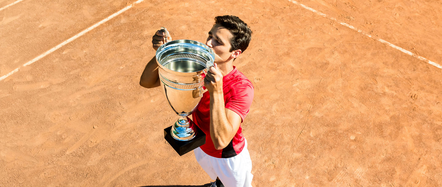 Mann hievt Pokal in die Luft und küsst ihn.