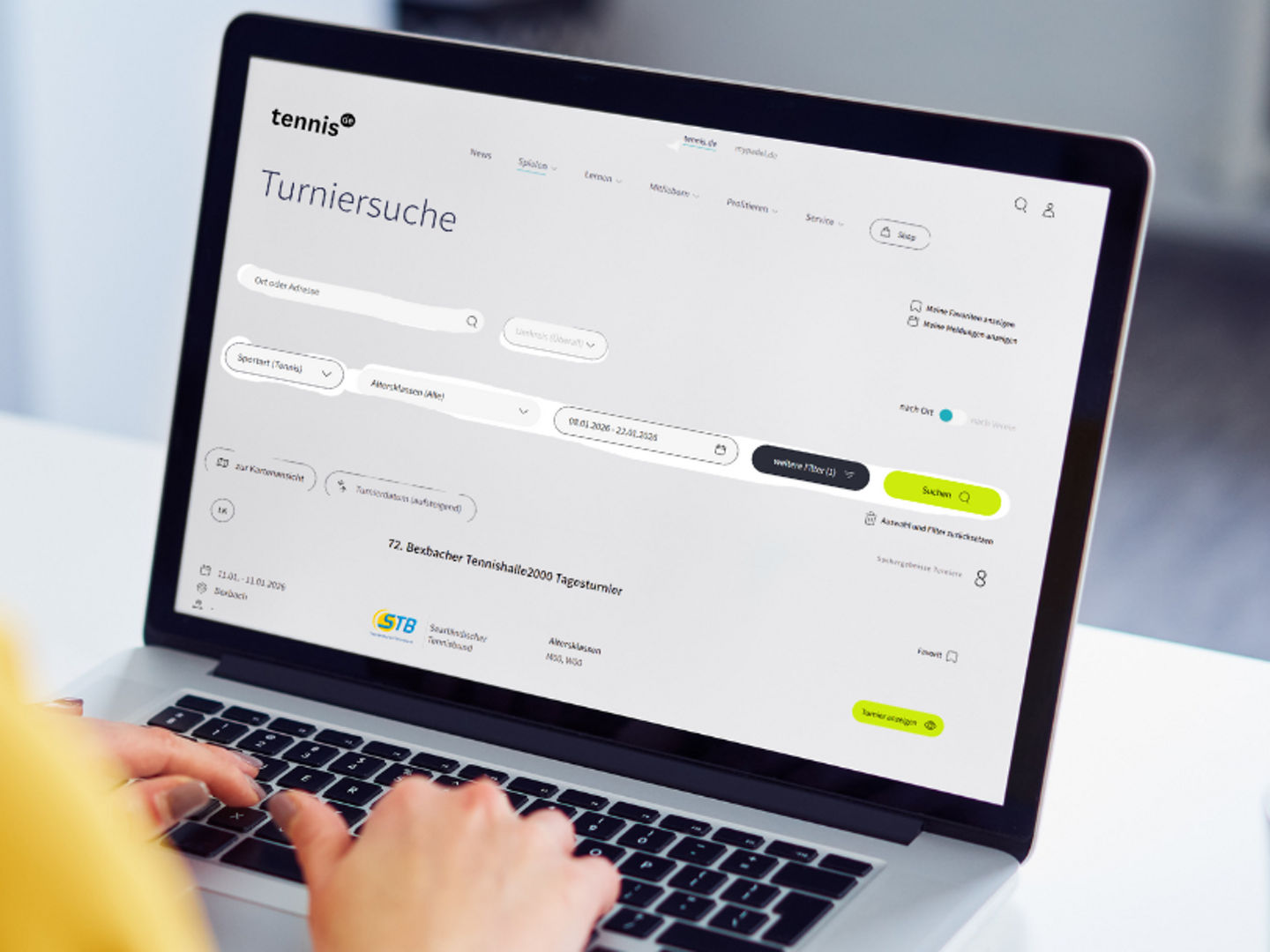 Blick über die Schulter einer Frau, die vor dem Laptop sitzt und dort gerade die tennis.de Turniersuche geöffnet hat