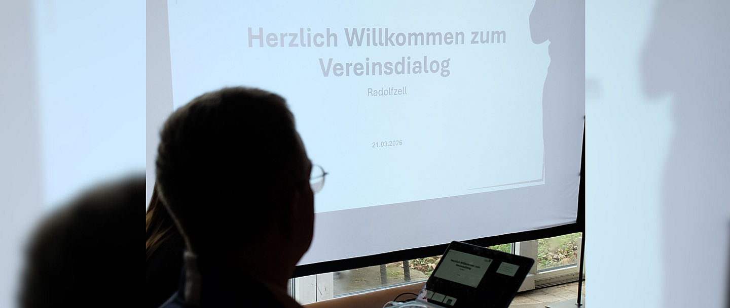 Willkommensfolie der PowerPoint Präsentation auf der Leinwand beim Vereinsdialog