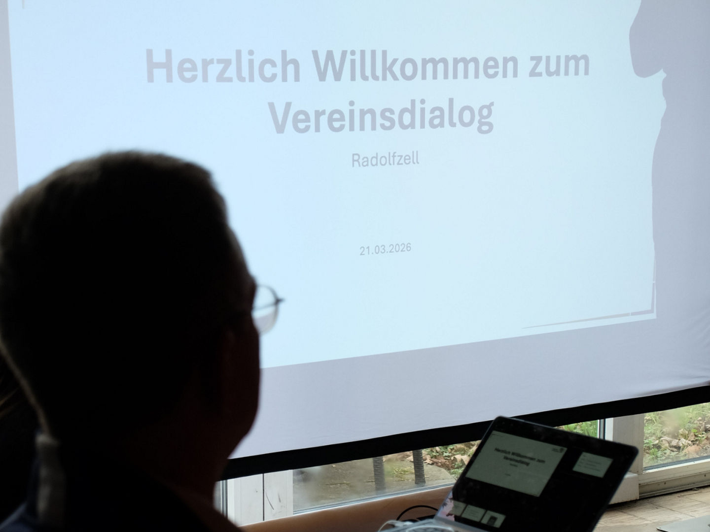Willkommensfolie der PowerPoint Präsentation auf der Leinwand beim Vereinsdialog