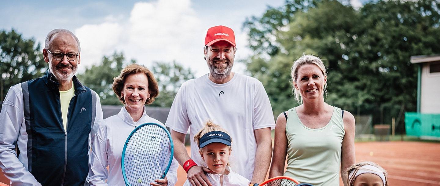 Eine Familie aus allen Generationen hinter dem Tennisnetz