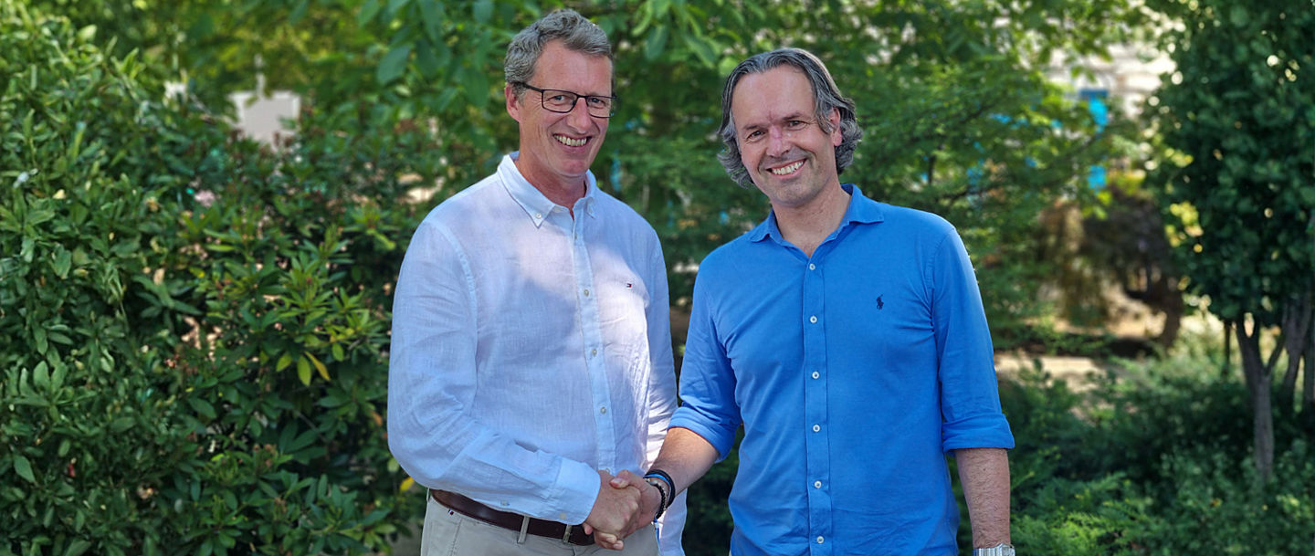 Stefan Bitenc und Marco van Maaren geben sich die Hand und lächeln dabei in die Kamera