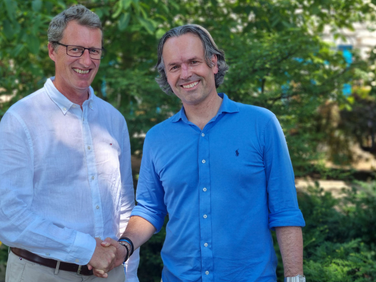 Stefan Bitenc und Marco van Maaren geben sich die Hand und lächeln dabei in die Kamera