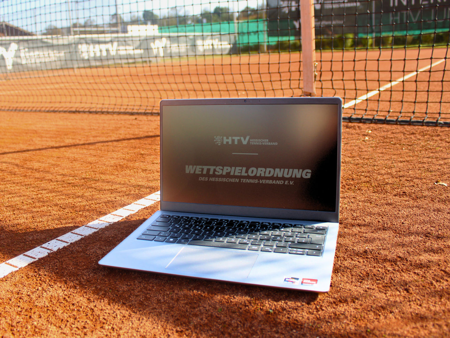 Laptop mit dem Titelbild "Wettspielordnung" auf einem Tennisplatz