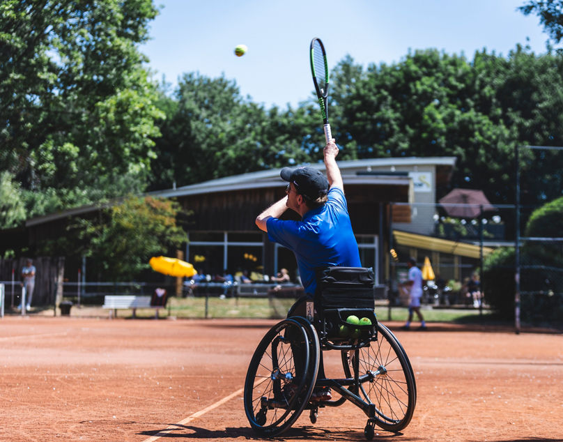 Bei den Deutschen Rollstuhltennismeisterschaften 2023 schlägt ein Spieler im Rollstuhl auf. Fotograf Mika Volkmann
