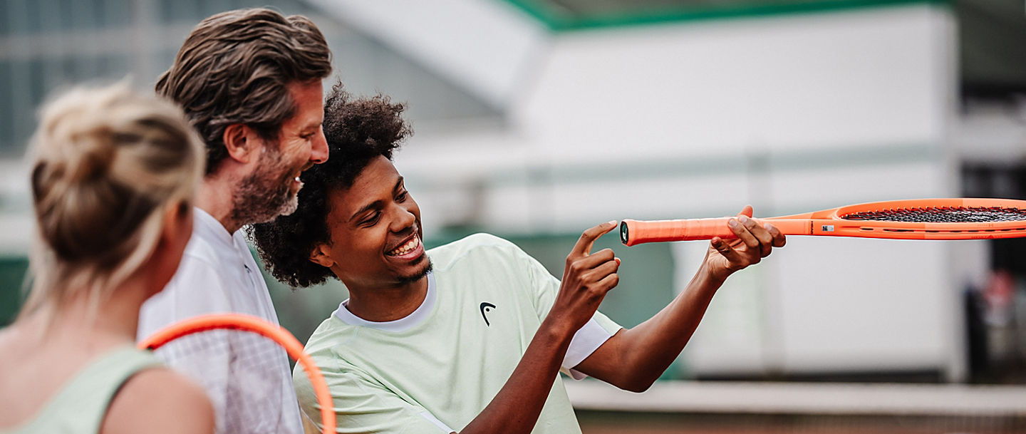 Trainer erklärt etwas auf dem Tennisplatz.