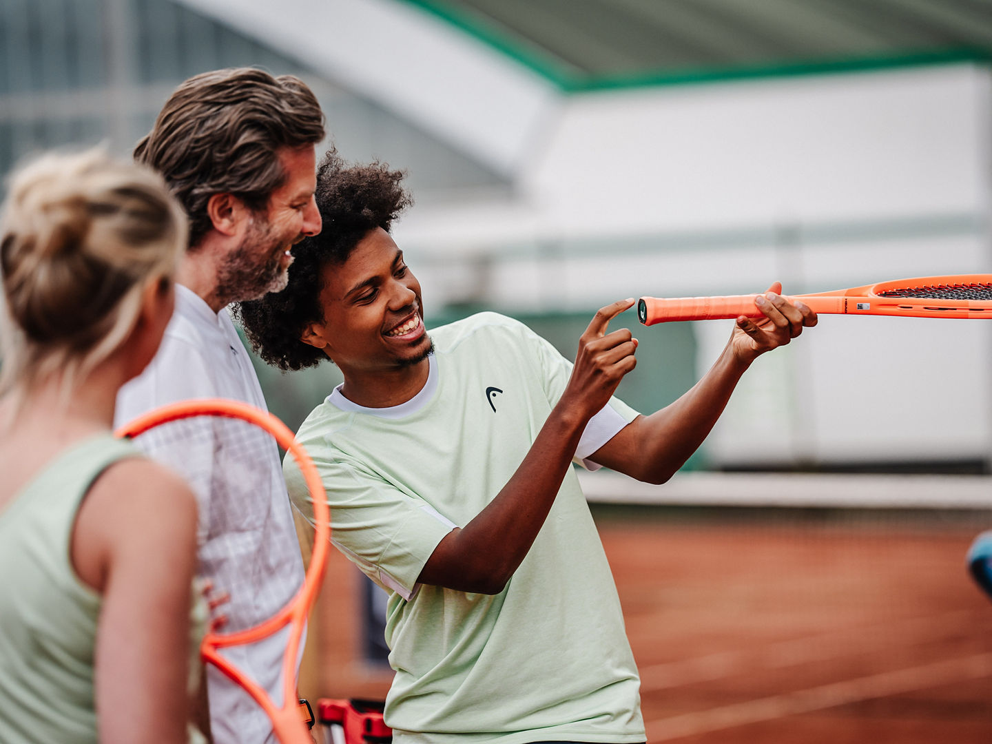 Trainer erklärt etwas auf dem Tennisplatz.