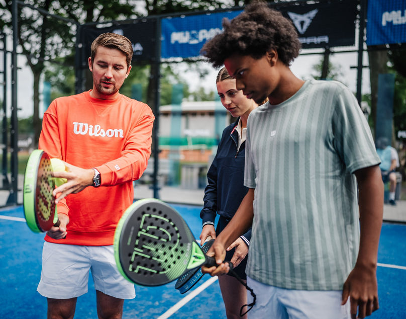 Trainer erklärt zwei Padelspieler:innen etwas